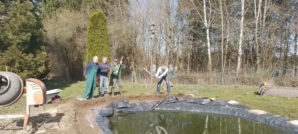 Vier Aktive Mitglieder des OGV Gilching graben den neuen Weg um den Teich aus.